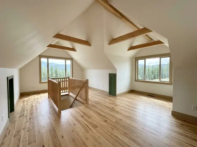 Illustration of a finished attic room with sloped ceilings and a new wooden staircase