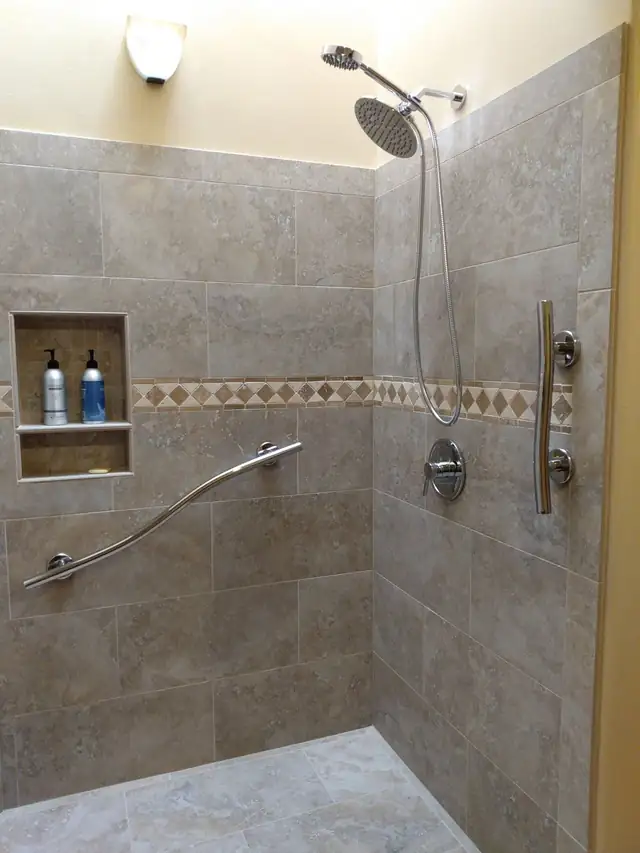 Tile shower wall with a recessed niche, diamond-pattern band and curved grab bar built by Liam and his apprentice