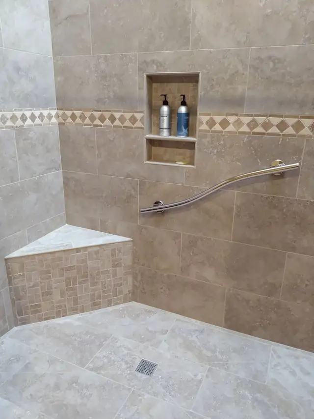 Tile shower with a corner bench, curved stainless grab bar, recessed niche and diamond-pattern border tile